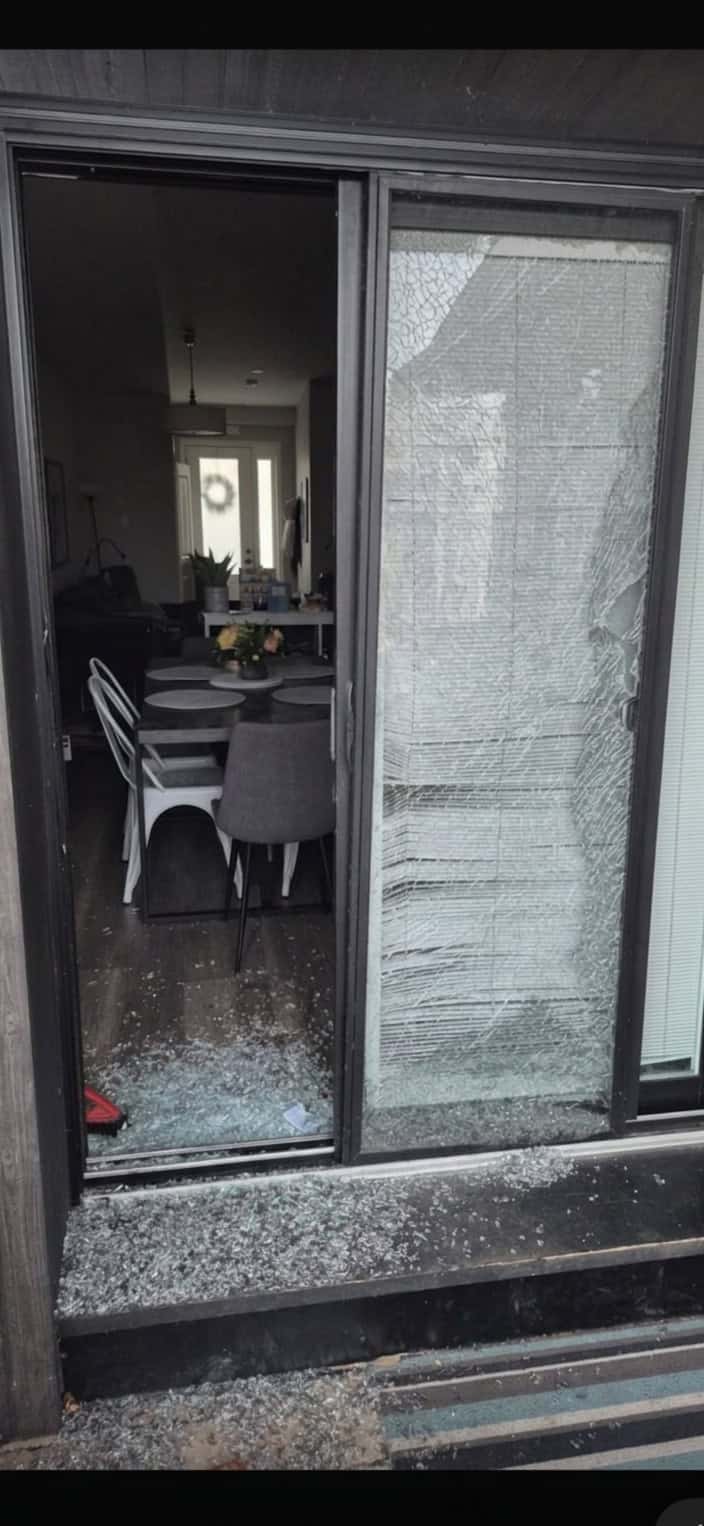Real job photo: a sliding patio door with one panel emptied out, broken glass piled on the threshold, the dining room visible inside